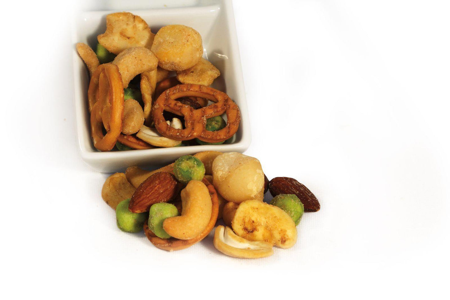 Babylon Mix - The Dormen Food Company. A picture of a small dish containing Babylon Mix from The Dormen Food Company, shows a few Pretzels, Macadamia nuts, wasabi peas, cashews and almonds. 